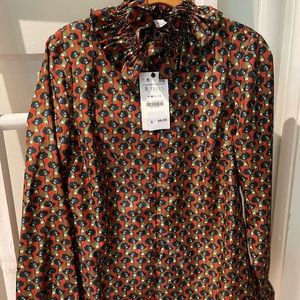 Long sleeve blouse with a high neck, ruffle trims and a button-up front.